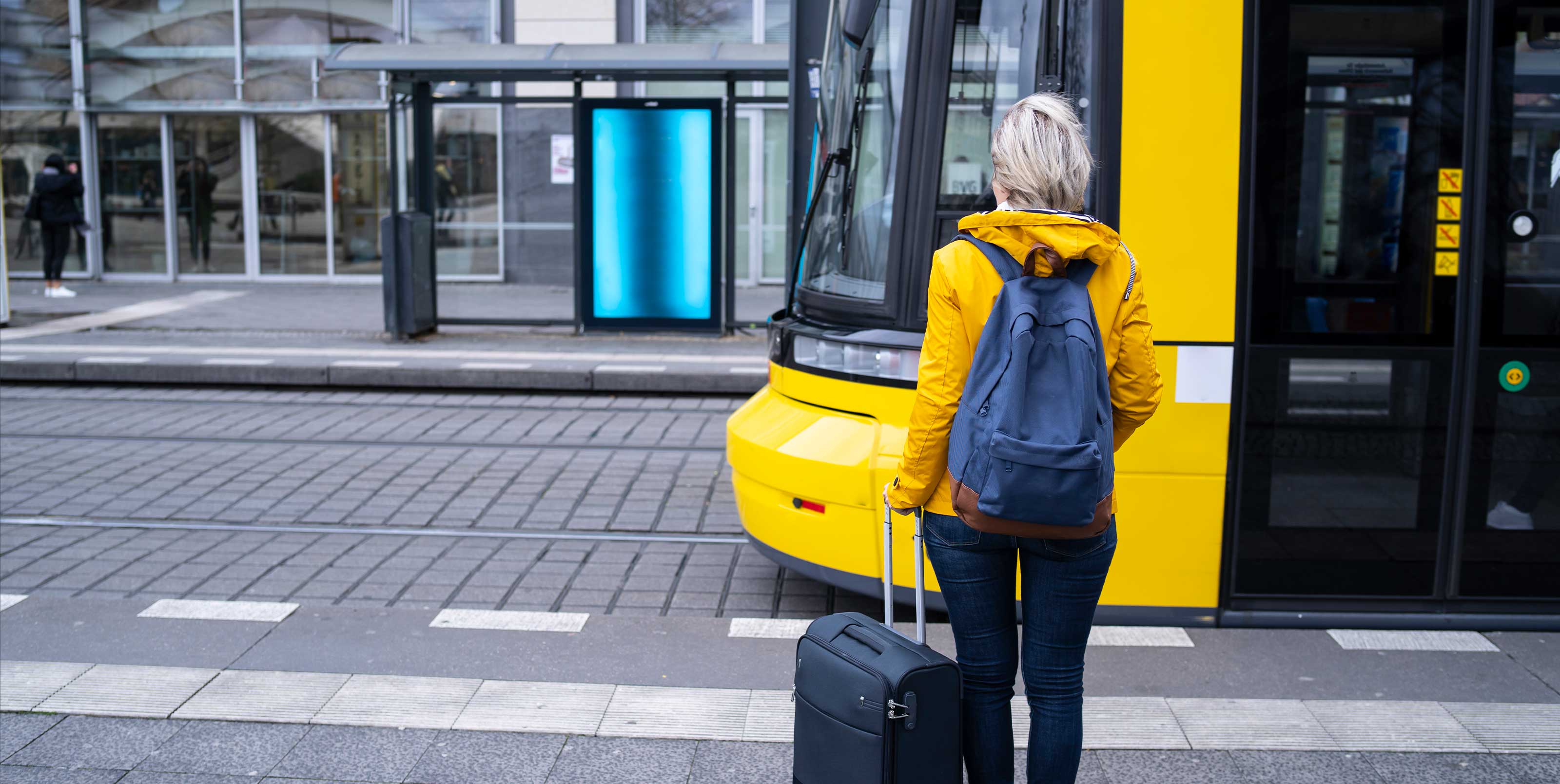 Woman with suitcase walks towards streetcar Woman with suitcase walks towards streetcar