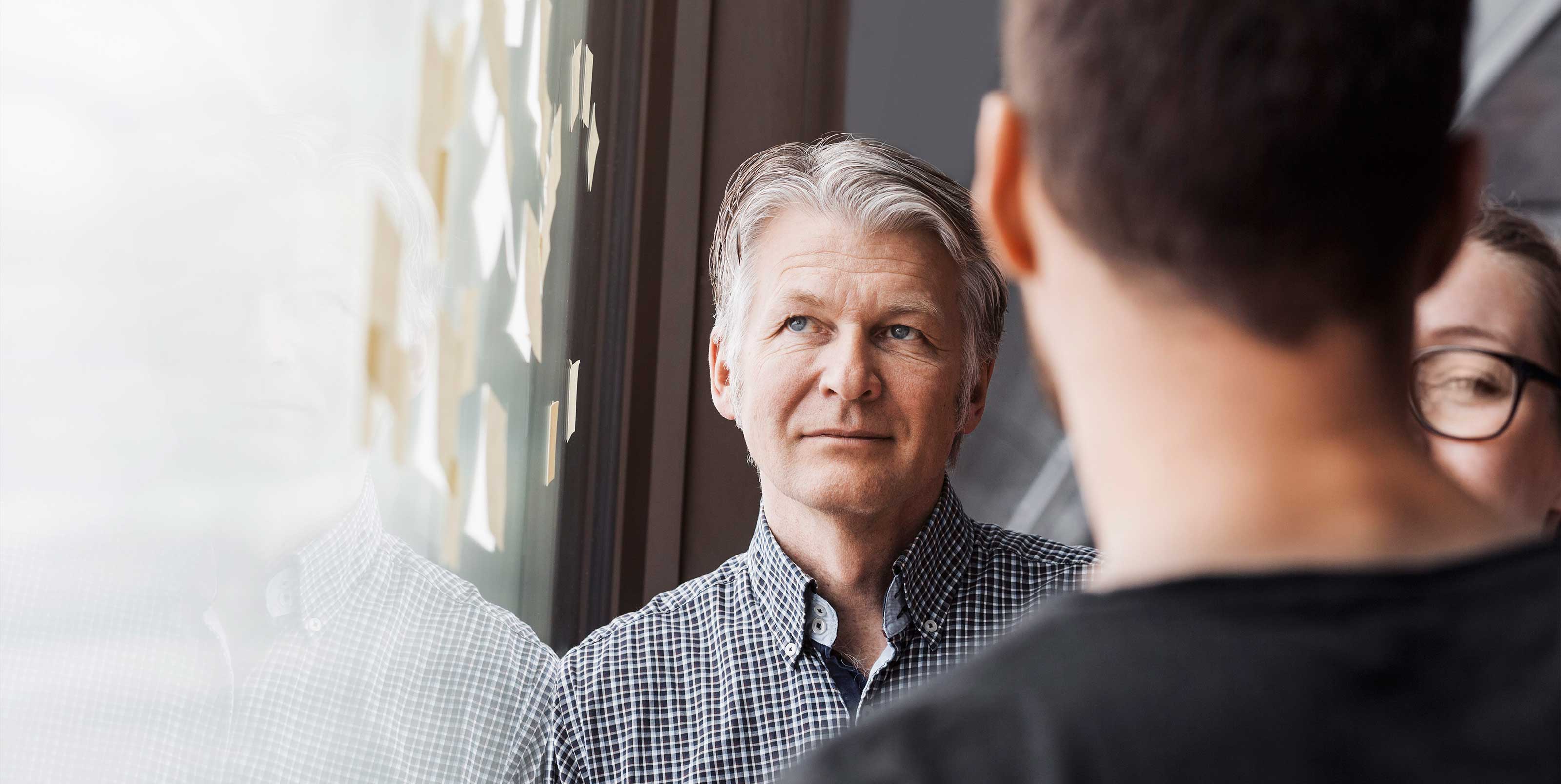 Man with thoughtful look in workshop with two other people