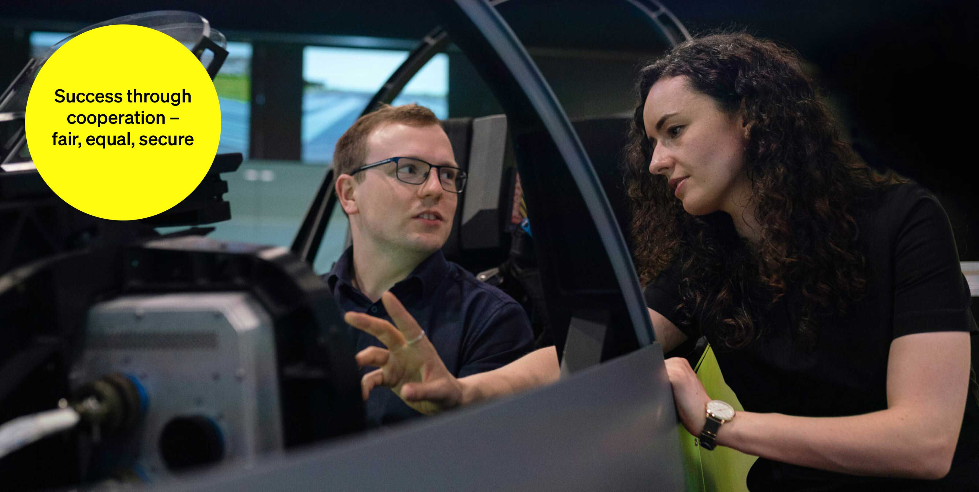 Two people talking in a video studio - text module in round tile: Success through cooperation: fair, equal, safe Two people talking in a video studio - text module in round tile: Success through cooperation: fair, equal, safe