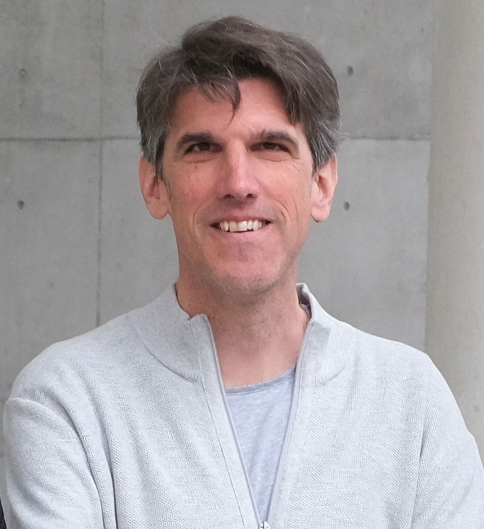 A smiling man in a grey top. A smiling man in a grey top.